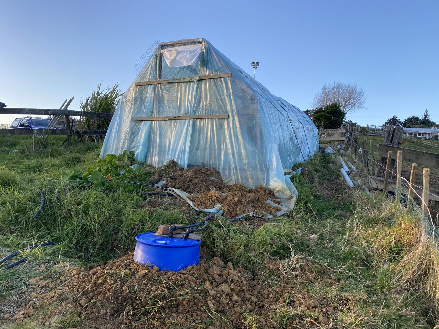 Hoop house with half-buried reservoir in front